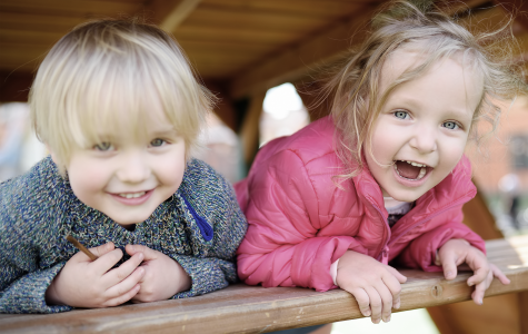 Dreng og pige på legeplads, smiler til fotografen