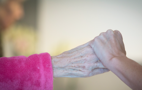 Ældre kvindehånd holder yngre hånd